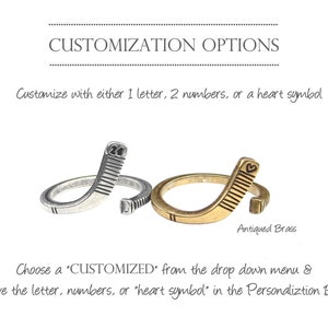 May include: Two hockey stick rings, one silver and one antique brass. The silver ring has the number "24" engraved on it. The brass ring has a heart symbol engraved on it. Customize with a letter, numbers, or a heart symbol.