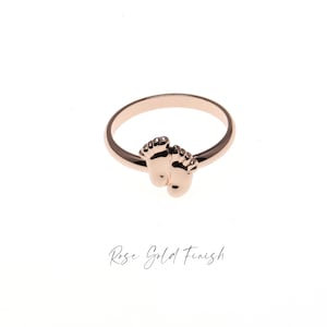 May include: A rose gold ring with two small baby footprints on the band.  Rose Gold Finish.