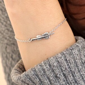 May include: A silver chain bracelet with a small violin charm.