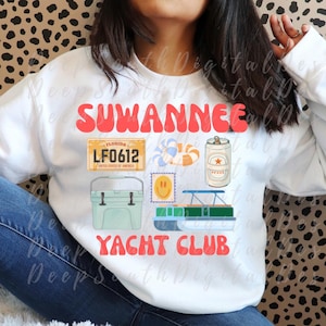 May include: White sweatshirt with the words "SUWANNEE YACHT CLUB" in red. The design includes a Florida license plate, a life preserver, a beer can, a cooler, and a stamp with a smiley face.