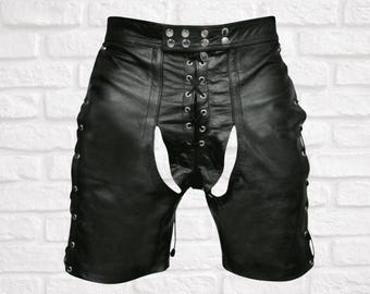 Könnte beinhalten: Schwarze Ledershorts mit einer Schnürung vorne, silberfarbenen Metallösen und einem mittigen Ausschnitt. Die Seiten der Shorts verfügen zudem über vertikale Schnürdetails mit passenden silbernen Ösen entlang der äußeren Seitennähte.