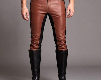 May include: Brown and black leather pants featuring a two-tone color block design with a front button closure, belt loops, and side pockets. The pants have a fitted silhouette and are paired with black leather knee-high boots. The text Attireo is visible.