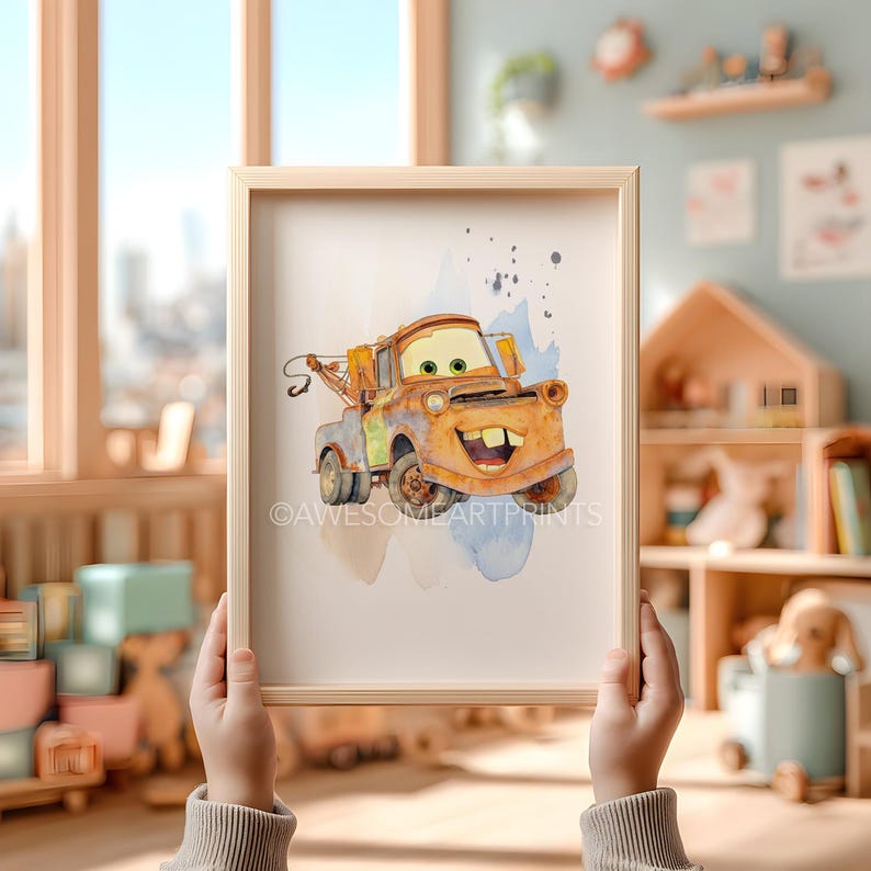 以下が含まれることがあります： 笑顔のオレンジ色のレッカー車のキャラクターが描かれた、額装された水彩画プリント。アートワークは、青と茶色の水彩アクセントで、使い古された外観をしています。フレームは明るい色の木材です。プリントは人が持っています。