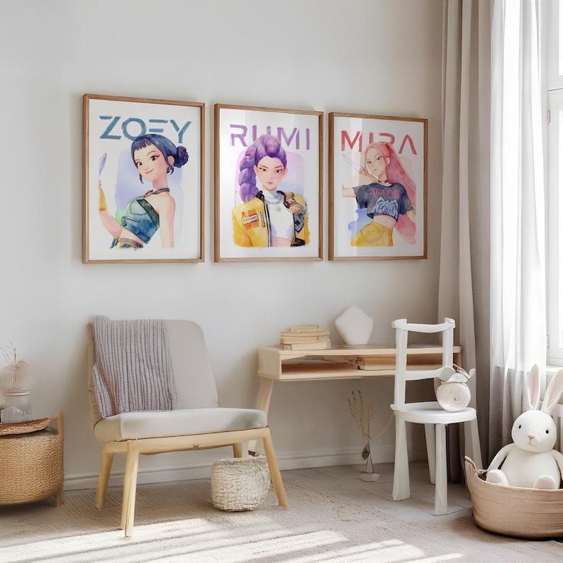 May include: Three framed art prints featuring watercolor illustrations of stylized female figures. Each print has a different name: Zoey, Rumi, and Mira, written in blue. The artwork is displayed in a light-filled room with a chair, desk, and a toy bunny.