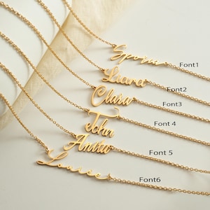 Könnte beinhalten: Sechs goldene Halsketten mit verschiedenen kursiven Schriftstilen, jede mit einem Namenspann. Die Namen sind: Sporia, Liara, Clara, John, Anita und Louise. Die Schriftarten sind mit Font 1 bis Font 6 gekennzeichnet.