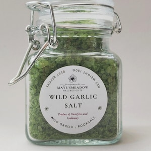 Op de afbeelding: Een glazen pot gevuld met groene wilde knoflooksoep. Het etiket luidt "Maye's Meadow Nature's Gifts Wild Garlic Salt Produce of Dumfries and Galloway Wild Garlic Rocksalt".