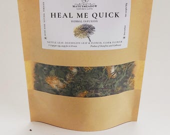 May include: A brown paper bag with a label that reads "Heal Me Quick Herbal Infusion" and lists the ingredients as nettle leaf, dandelion leaf & flower, and elder flower. The bag contains a blend of dried herbs, including green leaves, yellow flowers, and purple flower buds.