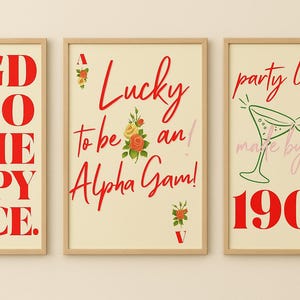 Puede incluir: Tres impresiones enmarcadas con fondos crema y texto rojo. Una dice "AGD IS SO THE HAPPY PLACE". Otra dice "Lucky to be an Alpha Gam!" con detalles florales. La tercera dice "party like it's 1904."