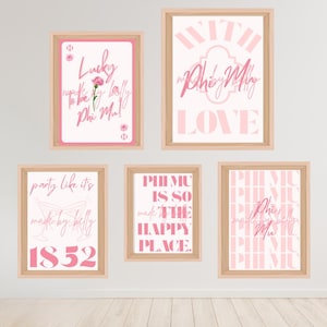 May include: Five framed art prints with pink text on a white background. The prints feature phrases like "Lucky to be a lady Phi Mu!" and "Phi Mu is so the happy place." The frames are light brown.