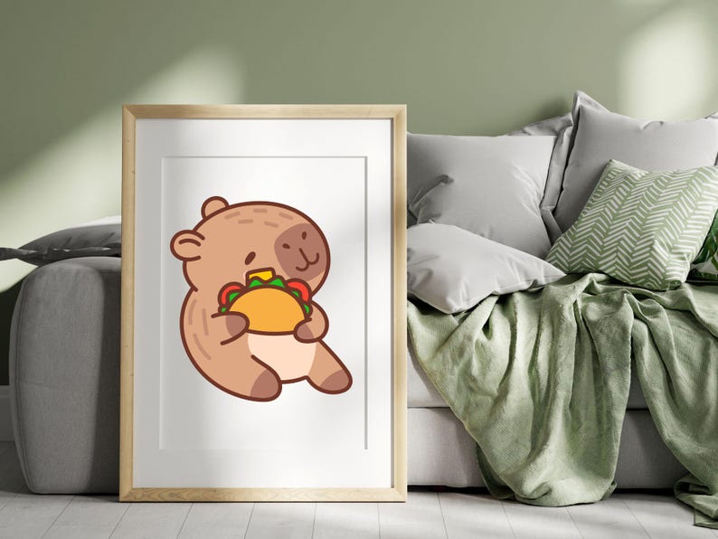 May include: A framed print featuring a cartoon bear holding a taco. The bear is brown with a light brown face and is sitting down. The taco has a yellow shell with green, red, and white fillings. The frame is light brown.