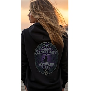 May include: Black hooded sweatshirt with a circular graphic on the back. The graphic features the text "Salem Sanctuary ESTD 1662" above a silhouette of a cat, with the words "For Wayward Cats" below. The design is in shades of purple and green.