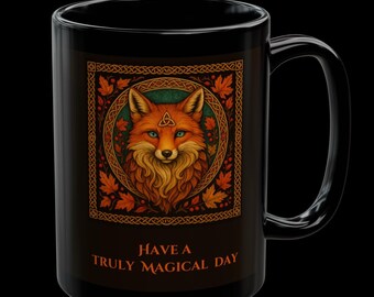 May include: Black ceramic mug featuring a detailed illustration of a fox with orange and brown fur, blue eyes, and a Celtic knot design. The mug includes the text "Have a Truly Magical Day" in orange. The mug has a large handle.