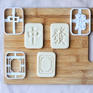 Könnte beinhalten: Ein Set aus drei Keramikbechern mit gesprenkelter, matter Oberfläche. Die Becher sind in Creme-, Hellgrau- und Dunkelgrautönen gehalten. Jeder Becher hat ein schlichtes, minimalistisches Design, ideal für Kaffee oder Tee.