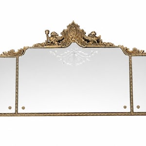 May include: A gold-toned, ornate mirror with a three-panel design. The mirror features elaborate carvings and decorative elements, including figures and floral motifs. The frame has a detailed, antique aesthetic.
