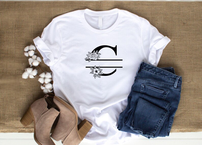 May include: White t-shirt with a black floral design and the letter "C" split in half with a line.