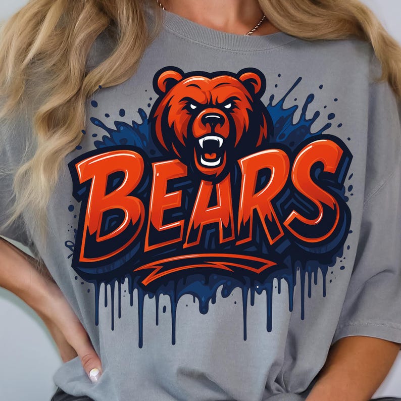 Może przedstawiać: Szara koszulka z efektowną grafiką niedźwiedzia w odcieniach pomarańczu i czerwieni, z napisem "BEARS" pogrubioną pomarańczową czcionką. Projekt zawiera niebieskie akcenty i efekty kapania, tworząc dynamiczny wygląd. Casualowy i sportowy element odzieży.