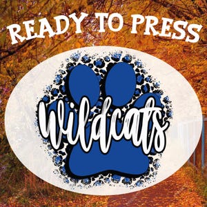 May include: An oval design featuring a blue paw print with the word "Wildcats" in white script. The paw print is surrounded by a blue and black leopard print pattern. The words "READY TO PRESS" are at the top.