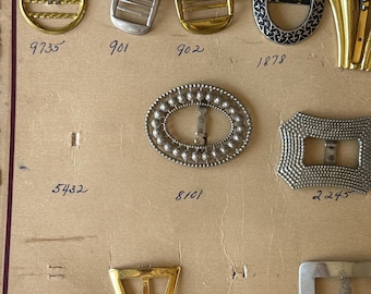 May include: A display board featuring various metal shoe buckles and ornaments labeled with model numbers. The collection includes circular, oval, and rectangular shapes in gold and silver tones, with textured, smooth, and patterned finishes.