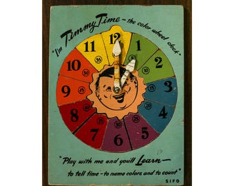 May include: Vintage "Timmy Time" color wheel clock. The clock face is divided into colorful segments, each with a number and a corresponding time in minutes. The clock features a smiling cartoon face in the center and the text "Play with me and you'll learn".
