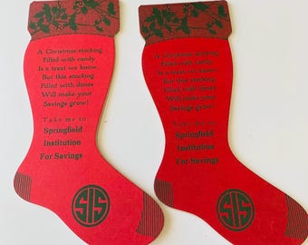 May include: Two red Christmas stocking-shaped cards with green text and accents. The cards have a poem about saving money and the text "Take me to Springfield Institution For Savings". Each card has a green "SIS" logo.