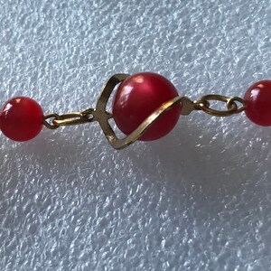 May include: A red and gold necklace with round beads and a chain link design.