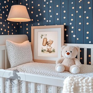 May include: A white crib with a white and black polka dot bedding set. A framed print of a teddy bear punching a punching bag hangs above the crib. A beige teddy bear sits on the crib. The wall behind the crib is navy blue with gold polka dots.
