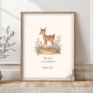 Könnte beinhalten: Ein gerahmter Druck mit einer Aquarellillustration eines Rehs in einem Feld mit Wildblumen. Der Text "The Lord is my shepherd Psalm 23:1" ist darunter in einer Serifenschrift gedruckt. Der Rahmen ist goldfarben.