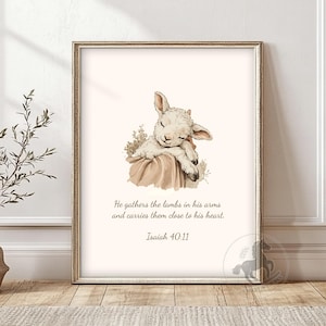 May include: A framed print with a watercolour illustration of a sleeping lamb. The lamb rests on a draped cloth, with floral accents. The text reads, "He gathers the lambs in his arms and carries them close to his heart. Isaiah 40:11."