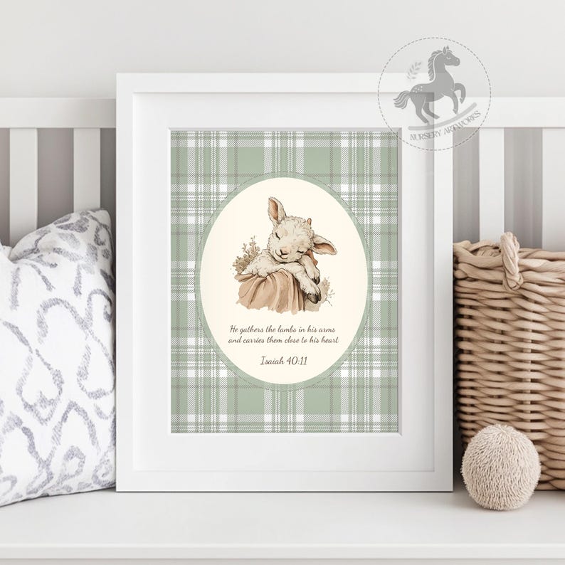 May include: A framed print featuring a sleeping lamb illustration in a soft, neutral color palette. The background has a green and white plaid pattern. The text reads, "He gathers the lambs in his arms and carries them close to his heart. Isaiah 40:11."