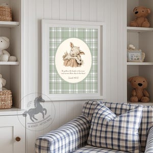 May include: A framed print featuring a sleeping lamb illustration within an oval, set against a green plaid background. The text reads "He gathers the lambs in his arms and carries them close to his heart Isaiah 40:11." The print is part of a nursery artwork collection.