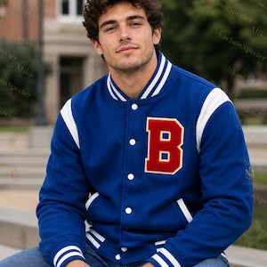 May include: A blue varsity jacket featuring white striped ribbed cuffs and collar, white sleeves, and a large red letter B with a yellow border on the left chest. The jacket has white snap buttons down the front and two side pockets with white trim.