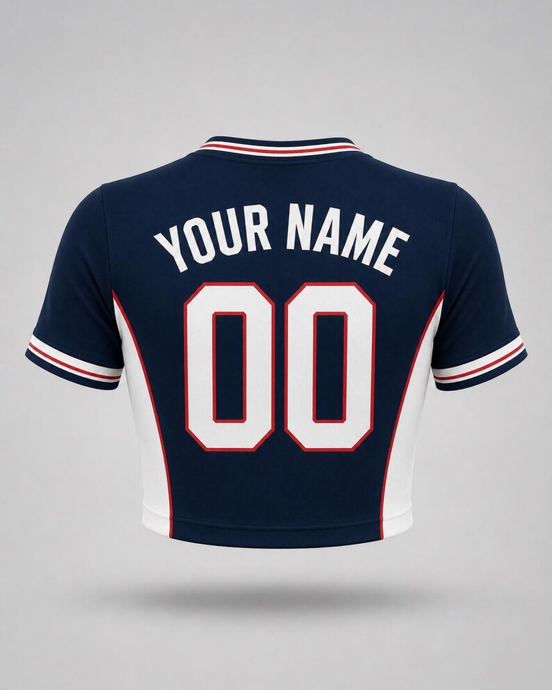 Navy blue crop top with white and red detailing. The back displays the text "YOUR NAME" above the number "00" in white with a red outline. The sleeves and collar have red and white stripes.
