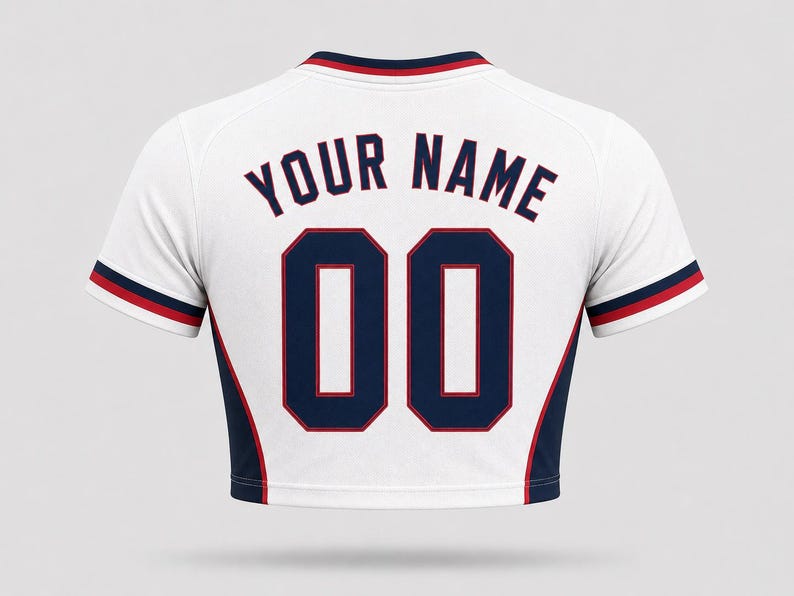 Back view of a women’s USA football home crop top in white, featuring customizable dark navy lettering “YOUR NAME” and number “00” with red outlines, navy side panels, and cropped fit