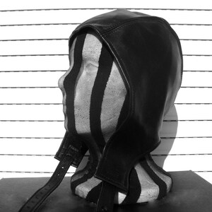 May include: A black leather balaclava with a long strap. The balaclava is on a striped mannequin head.