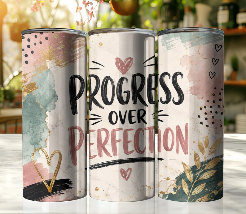 May include: Three cylindrical tumblers featuring a white marble background with abstract watercolor splashes in pink, sage green, and gold. The center tumbler displays the black text "PROGRESS OVER PERFECTION" with small pink hearts and black dots.