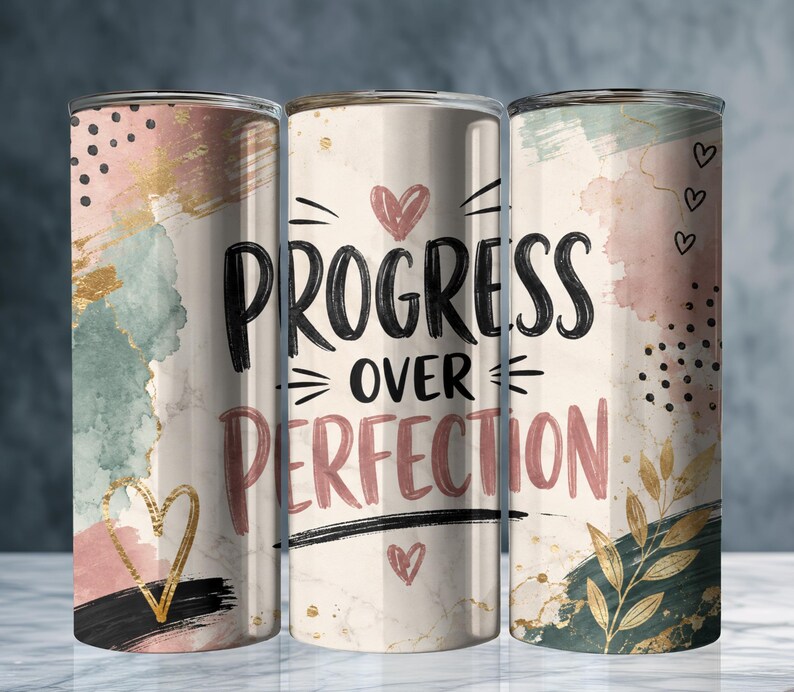 May include: Three cylindrical tumblers featuring a cream background with abstract watercolor splashes in sage green, dusty pink, and gold. The center tumbler displays the black and pink text "PROGRESS OVER PERFECTION" with small heart icons and gold leaf accents.