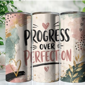 May include: A cylindrical tumbler featuring a cream-colored background with abstract watercolor splashes in pink, sage green, and gold. The text "PROGRESS OVER PERFECTION" is printed in black and muted pink, accented by small heart icons, black dots, and gold leaf foliage.