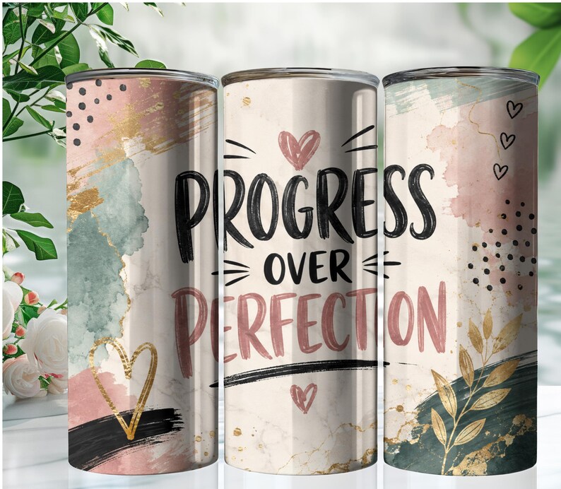 May include: A cylindrical tumbler featuring a cream-colored background with abstract watercolor splashes in pink, sage green, and gold. The text "PROGRESS OVER PERFECTION" is printed in black and muted pink, accented by small heart icons, black dots, and gold leaf foliage.