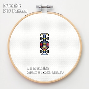 Può includere: Un modello a punto croce di un'auto da corsa in un telaio da ricamo in legno. L'auto è principalmente blu, rossa, gialla e nera. Il testo "Printable PDF Pattern" è in alto. Il modello misura 1,45 cm x 3,81 cm e ha 8 x 21 punti.