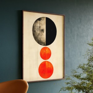 May include: A framed abstract art print with a large black and white circle at the top and two smaller orange circles below. The background is a light beige color.