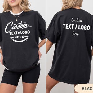 May include: Black oversized t-shirt with the text "Custom TEXT OR LOGO HERE" in white script and block letters. The back of the shirt also features the text "Custom TEXT / LOGO here".