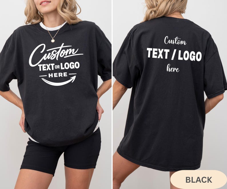 May include: Black oversized t-shirt with the text "Custom TEXT OR LOGO HERE" in white script and block letters. The back of the shirt also features the text "Custom TEXT / LOGO here".