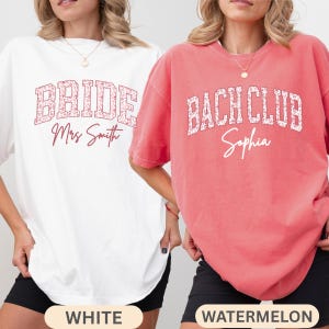May include: Two oversized t-shirts, one white and one watermelon. The white shirt says "BRIDE Mrs Smith" in a floral design. The watermelon shirt says "BACH CLUB Sophia" in a similar floral design. Both shirts have a crew neck.