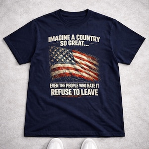 Könnte beinhalten: Marineblaues T-Shirt mit einem verblassten amerikanischen Flaggen-Design und weißem Text. Der Text lautet: "IMAGINE A COUNTRY SO GREAT... EVEN THE PEOPLE WHO HATE IT REFUSE TO LEAVE". Das T-Shirt hat einen Rundhalsausschnitt.