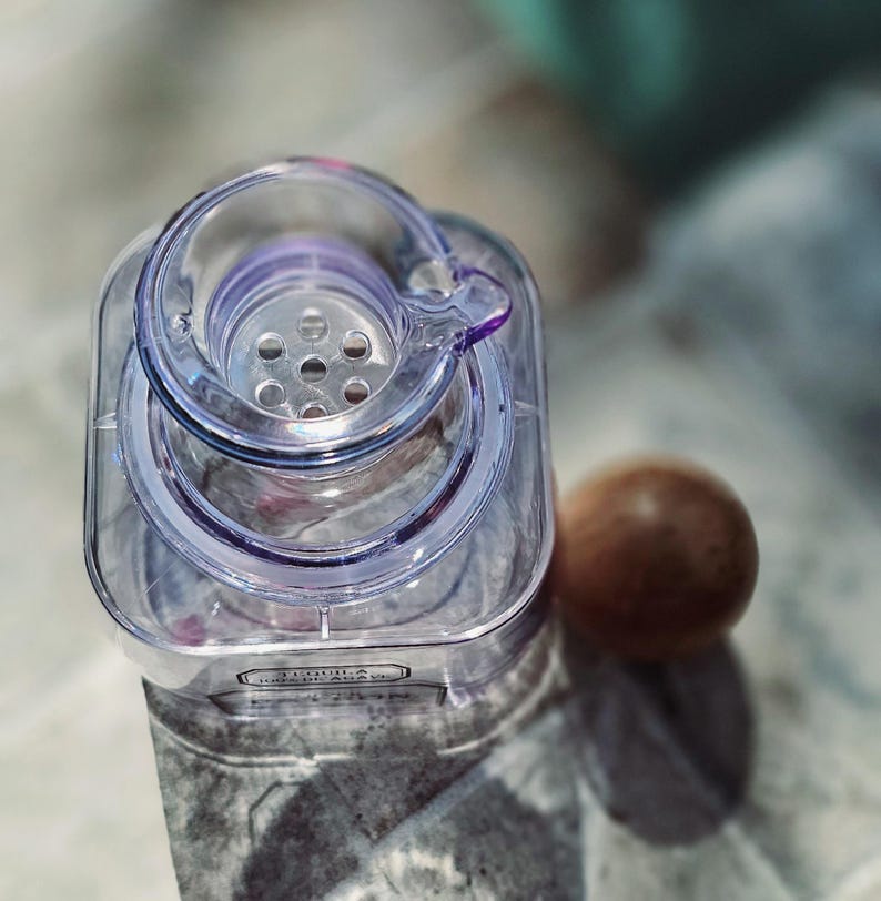 May include: A clear plastic bottle with a lid that has a strainer. The bottle has a label that says "Java" on it.