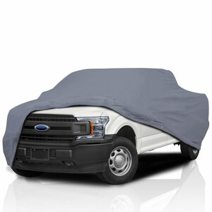 Könnte beinhalten: Eine graue LKW-Abdeckung über einem weißen Pickup-Truck. Die Abdeckung verdeckt den Großteil des Fahrzeugs, wobei der vordere Kühlergrill, die Scheinwerfer und die Räder sichtbar sind. Das Ford-Emblem ist vorne zu sehen.
