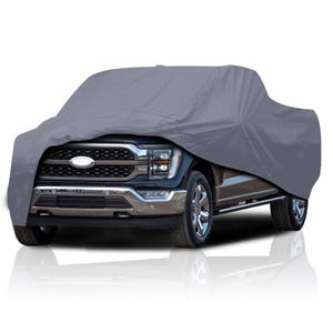 May include: A gray truck cover draped over a black pickup truck. The cover conceals the truck's body, with the front grille, headlights, and chrome bumper visible. The truck is parked on a white surface.
