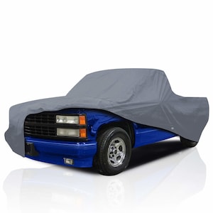 Puede incluir: Una funda gris para camión sobre una camioneta azul. La funda está hecha de un material liso y duradero, diseñado para proteger el vehículo de los elementos. El camión tiene ruedas cromadas y una parrilla negra.