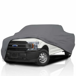 Könnte beinhalten: Eine graue LKW-Abdeckung über einem weißen Pickup-Truck. Die Abdeckung verdeckt den Großteil des Fahrzeugs, aber der vordere Kühlergrill, die Scheinwerfer und die Räder sind sichtbar. Das Ford-Emblem ist vorne sichtbar.