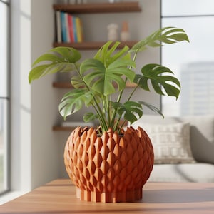May include: A potted Monstera plant with large, green, split leaves sits in a decorative, textured, orange-brown pot. The pot has a unique, geometric design. The plant is on a wooden table in a well-lit room.
